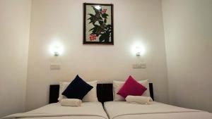 two beds with colorful pillows in a room at Sea Breeze Hotel in Mirissa