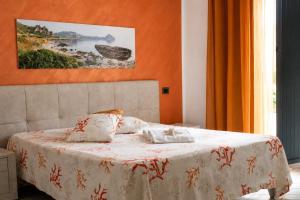a bedroom with a bed with an orange wall at Monte Monaco B&B in San Vito lo Capo