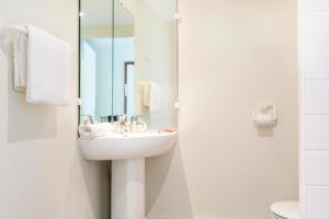ein Badezimmer mit Waschbecken und Spiegel in der Unterkunft Hôtel Les Gens De Mer Dunkerque by Popinns in Dunkerque