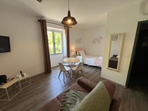 a living room with a couch and a table and a bed at Logis Hôtel Auberge de Cartassac in Sarrazac