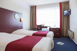 ein Hotelzimmer mit zwei Betten und einem Fenster in der Unterkunft Hôtel Les Gens De Mer Dunkerque by Popinns in Dunkerque