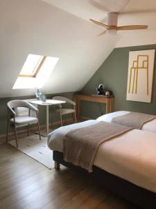 a bedroom with two beds and a table and a window at La maison Buis chambres d hotes in Quiestède