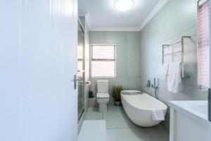 a bathroom with a tub and a toilet and a sink at Rosebud 4 Beacon Point in Mossel Bay +36 photos