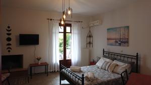 a bedroom with a bed and a tv and a window at Vagionia Apartments in Ancient Epidauros