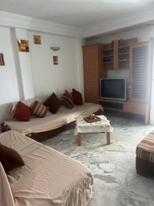 a living room with two beds and a flat screen tv at S1 a louer in Dar el Saïd