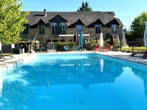a swimming pool in front of a house at Logis Hôtel Auberge de Cartassac in Sarrazac