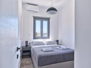 a white bedroom with a bed and a window at Mouragio Stay - Aliki , Paros in Aliki