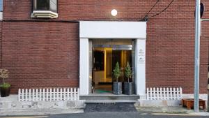 a red brick building with a doorway with two potted plants at Air Jinju in Jinju