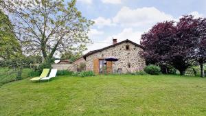 a stone house with two benches in a yard at Le clédier de cherveix in Solignac