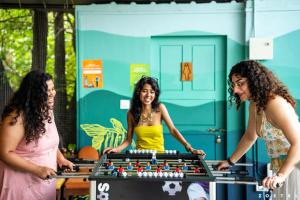 a group of three women standing around a pool table at Zostel Kochi, Kumbalangi in Cochin