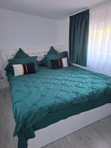 a bed with green sheets and pillows in a bedroom at Casuța Râului in Zărneşti