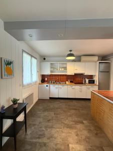 a large kitchen with white cabinets and a table at Casa Limon, Charm & Serenity in Cesson-Sévigné