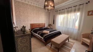 a bedroom with a bed and a chair and a chandelier at Villa Michel in Tamraght Ouzdar