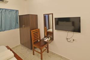 a room with a desk and a tv and a chair at Hotel De Lux Splendid in Pondicherry