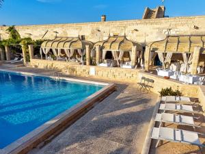 a pool at a hotel with white chairs and a building at Hotiday Torre Santo Stefano Resort in Otranto