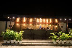 a restaurant with a bar with lights and potted plants at Peridott Inn in Jaigaon