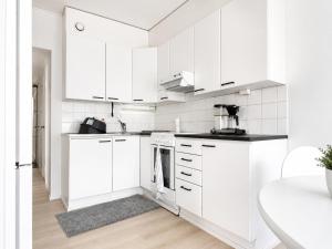 a white kitchen with white cabinets and a table at Aava's apt. FREE Parking in Pori