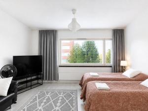 a hotel room with two beds and a flat screen tv at Aava's apt. FREE Parking in Pori