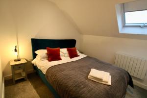 a bedroom with a bed with red pillows and a window at Penthouse new 2 bed 2 apartment in Basingstoke