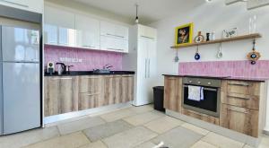 a kitchen with wooden cabinets and a pink accent wall at Blue Marine in Kalogrea