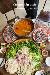 a table topped with plates of food and a pot of soup at Bản Lướt Homestay -Ngọc Chiến Hotspring in Sơn La