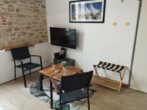 a living room with a table and chairs and a television at studio moderne les pieds dans l'eau in Larmor-Baden
