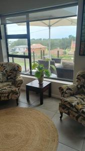 a living room with two chairs and a table and a window at Hartmel Sea Deck in Hartenbos +5 photos