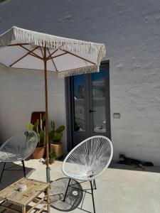 two chairs and an umbrella and a table and chairs at Ma'Bella - MASSERIA PICCOLA by Rentbeat in Cisternino