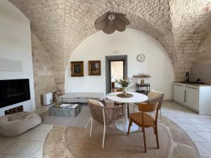 a living room with a table and a kitchen at Ma'Bella - MASSERIA PICCOLA by Rentbeat in Cisternino