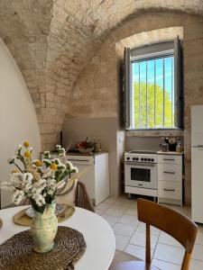 a kitchen with a table with a vase of flowers at Ma'Bella - MASSERIA PICCOLA by Rentbeat in Cisternino