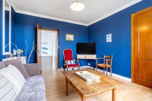a living room with blue walls and a wooden table at L'escale bleue in Plomeur