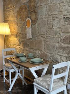 ein Holztisch mit Stühlen und eine Steinmauer in der Unterkunft Stone Nest in Tochni