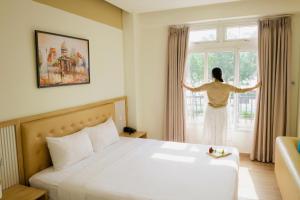 a woman looking out the window of a hotel room at Palmier Hotel - Art House Da Nang in Danang
