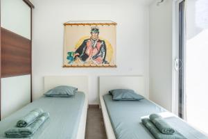 two beds in a room with a painting on the wall at La maison du verger in Loctudy