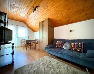 a living room with a blue couch and a wooden ceiling at Kovács Vendégház in Harkány