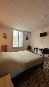 a bedroom with a large bed and a table at Hotel restaurant LAISSAC SPEISER in Olargues