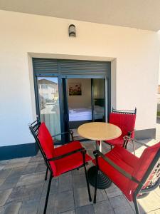 a patio with red chairs and a table and a bedroom at Domus Klek in Kučinić-Selo