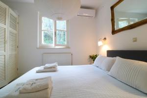 a bedroom with a large white bed with a mirror at Guesthouse Thomas in Vátos