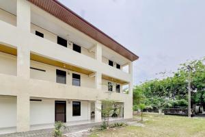 a large white building with trees in front of it at Urbanview Hotel MD Residence in Sunggal