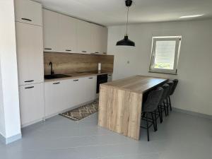 a kitchen with white cabinets and a wooden table at Panorama in Drvenik Veli