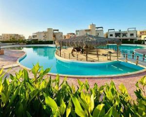 a large swimming pool with a straw umbrella and some buildings at شاليه ديمورا عائلات فقط Dimora Chalet Only Family in Dawwār Muḩammad Abū Shunaynah
