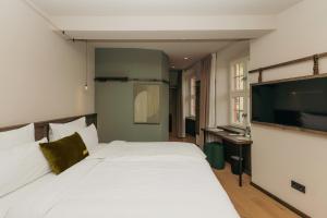 a bedroom with a large white bed and a flat screen tv at HOY bamberg boutique hotel in Bamberg
