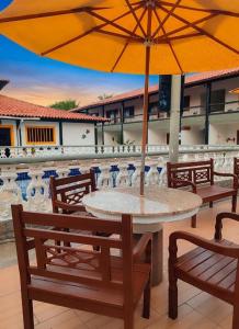 a table and chairs with an umbrella on a roof at Refúgio Peró - Praia, piscina e churrasqueira in Cabo Frio