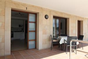 a patio with a table and chairs and a clock at Apartamentos Los Novalejos in Arnuero