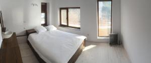 a bedroom with a bed with white sheets and two windows at Sabri's Penthouse in Ogled