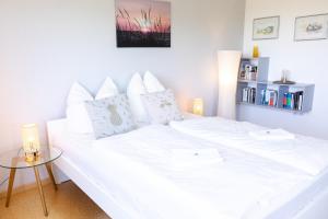 a white bed in a room with a table at Strandnahe Ferienwohnung mit Privatweg, Spielplatz & Aufzug in Sankt Peter-Ording