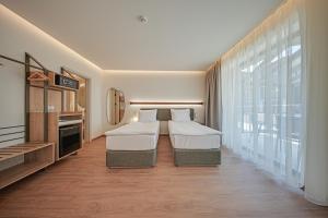 a hotel room with two beds and a large window at Aparthotel SamElyon in Samokov