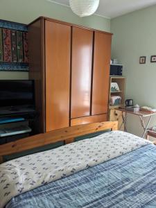 a bedroom with a bed and a large wooden cabinet at Camera con bagno in villa in Pieve Emanuele