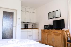 a bedroom with a bed and a tv and a kitchen at Strandnahe Ferienwohnung mit Privatweg, Spielplatz & Aufzug in Sankt Peter-Ording