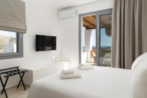 a white room with two beds and a window at Spanos Apartments - Andros in Agios Petros